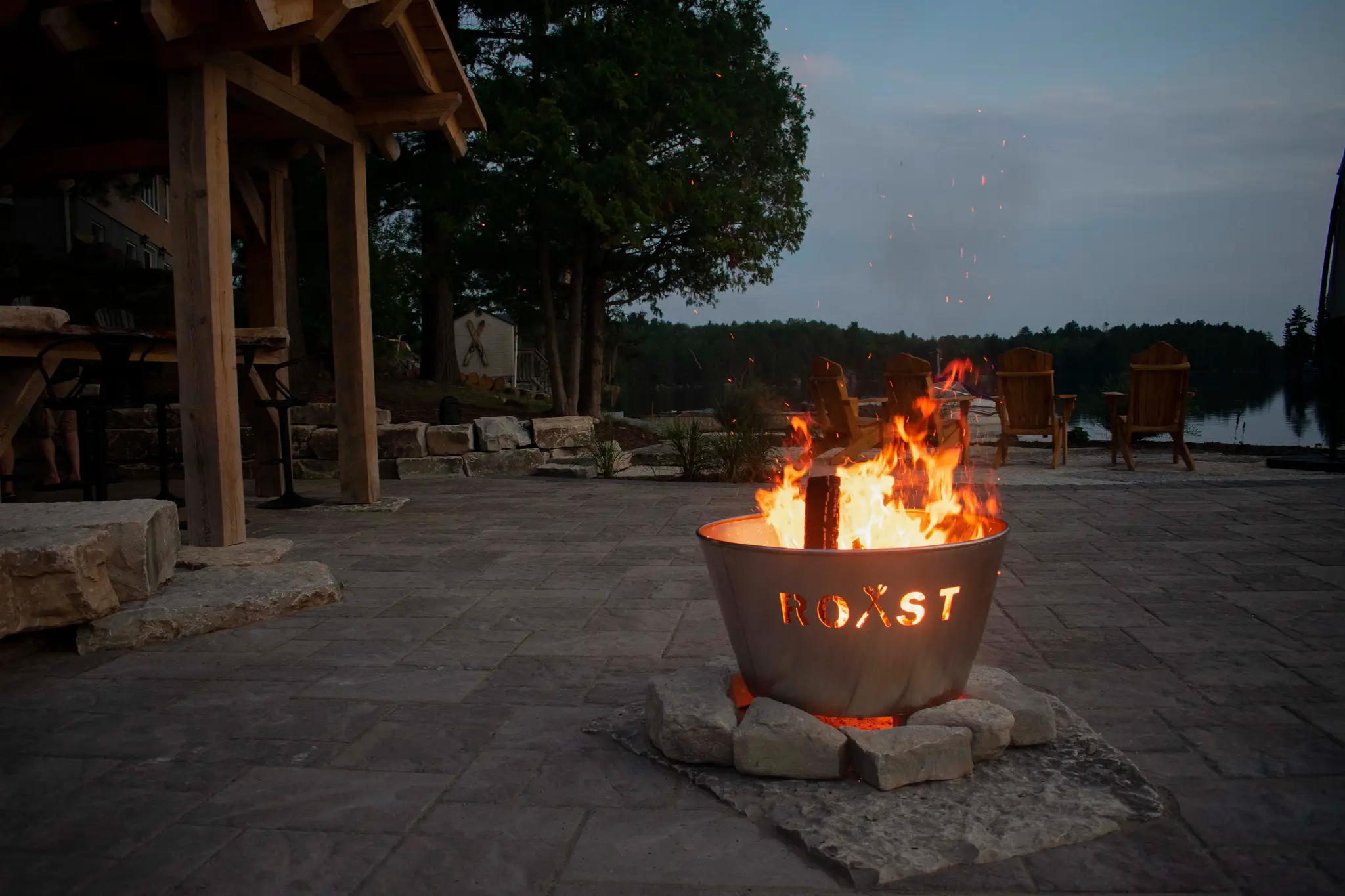 Custom fire pit glowing at dusk on a natural stone patio at Nepawassi Lake