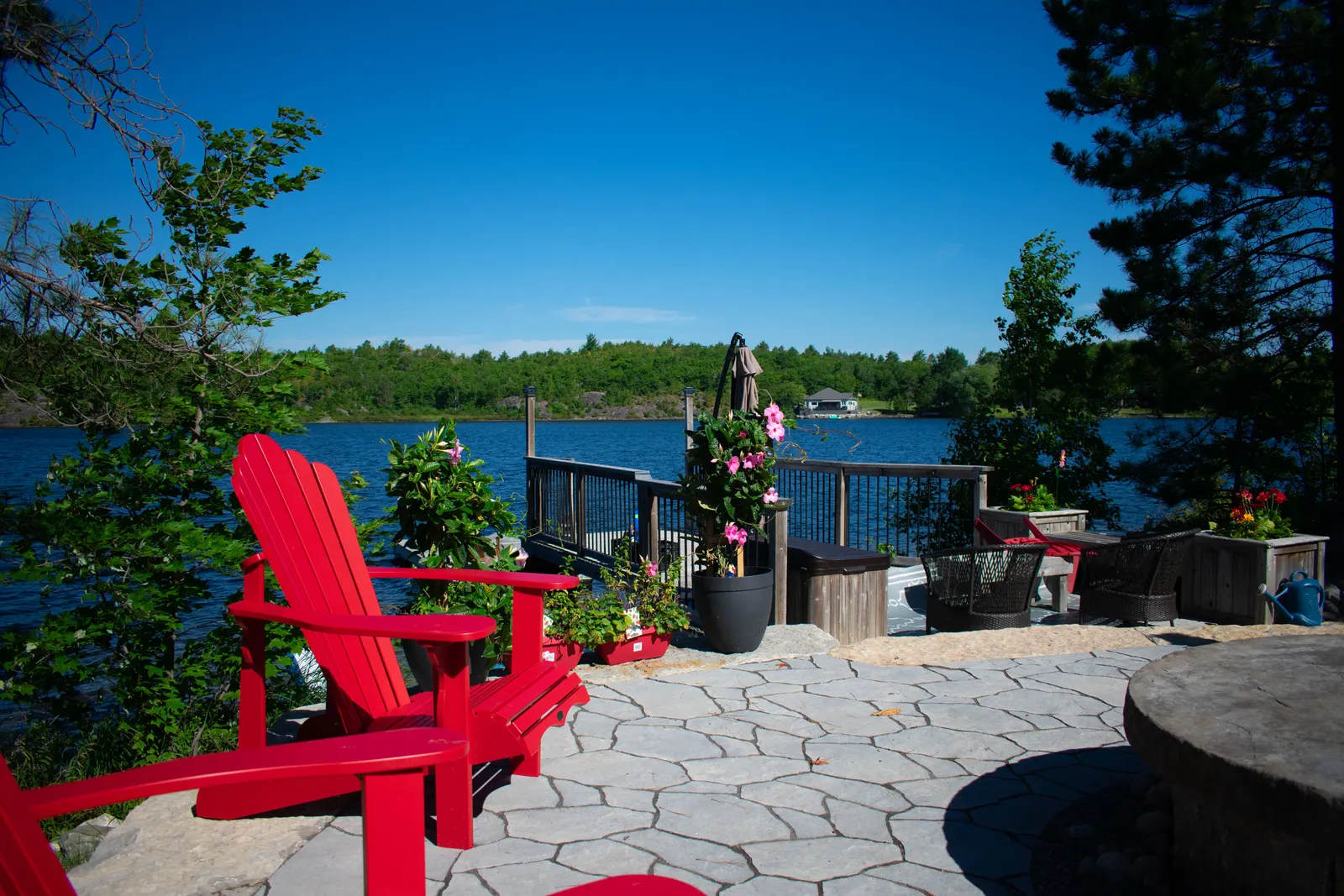 Flagstone patio with a red Adirondack chair overlooking the lake