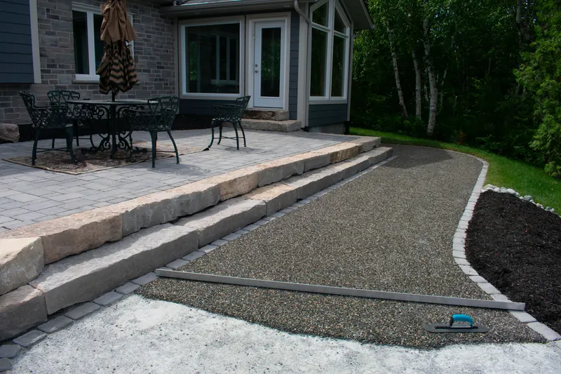Paver patio and curved walkway connecting to a stone step-down