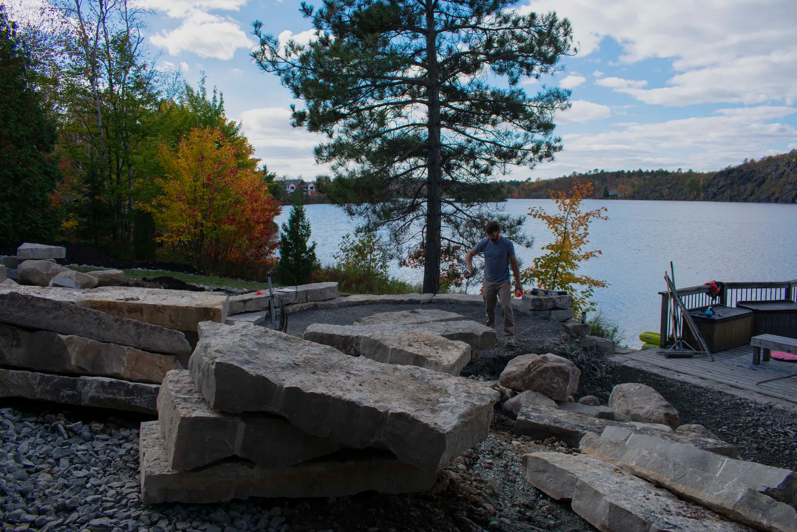 Large armour stone staged on site along the lake shoreline in autumn