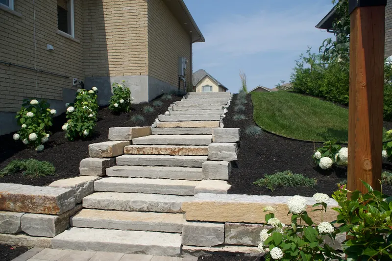 Finished natural stone staircase along the same path, framed by hydrangeas